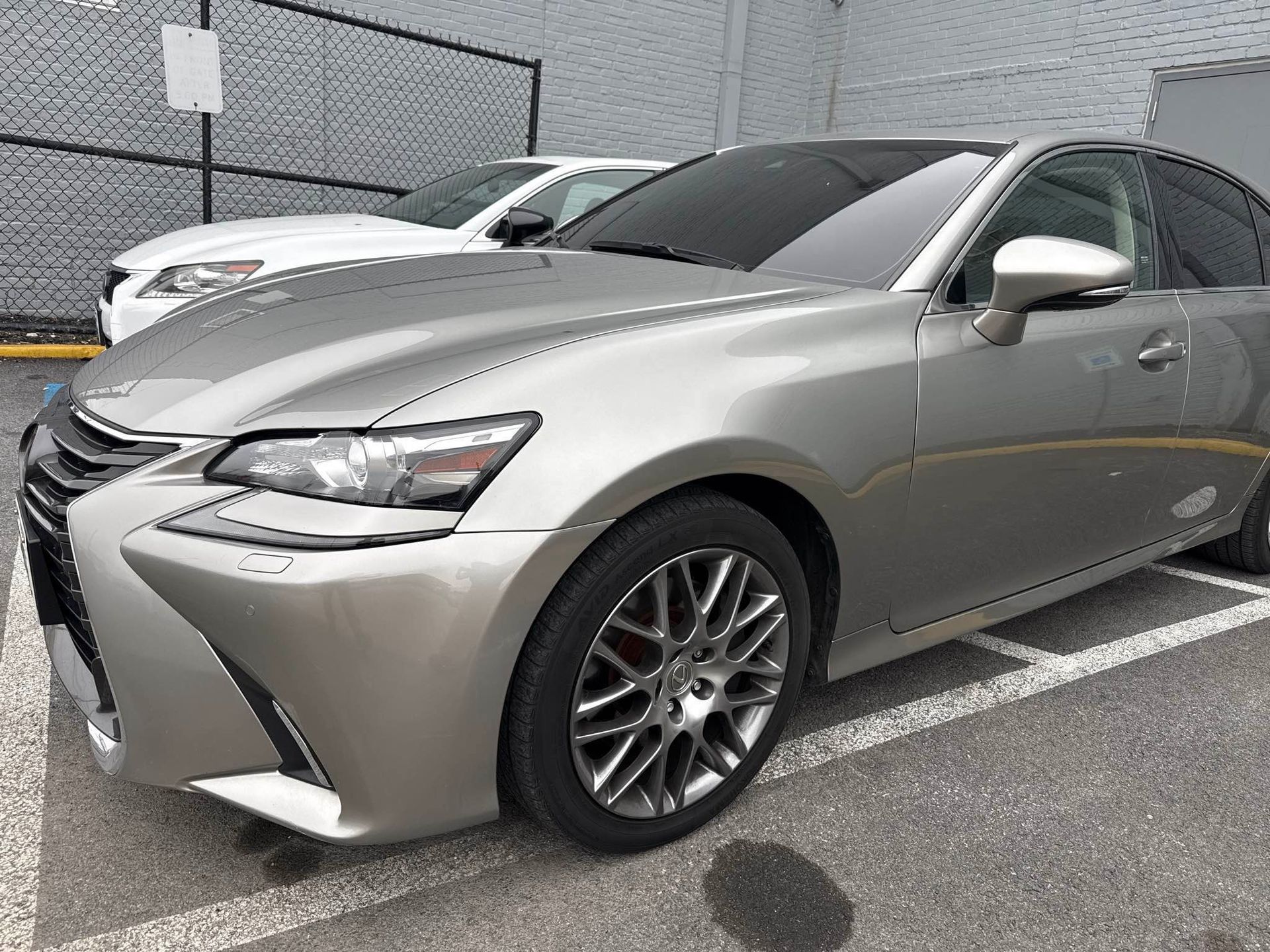 Silver Lexus sedan parked in a lot, with a white Lexus behind it.