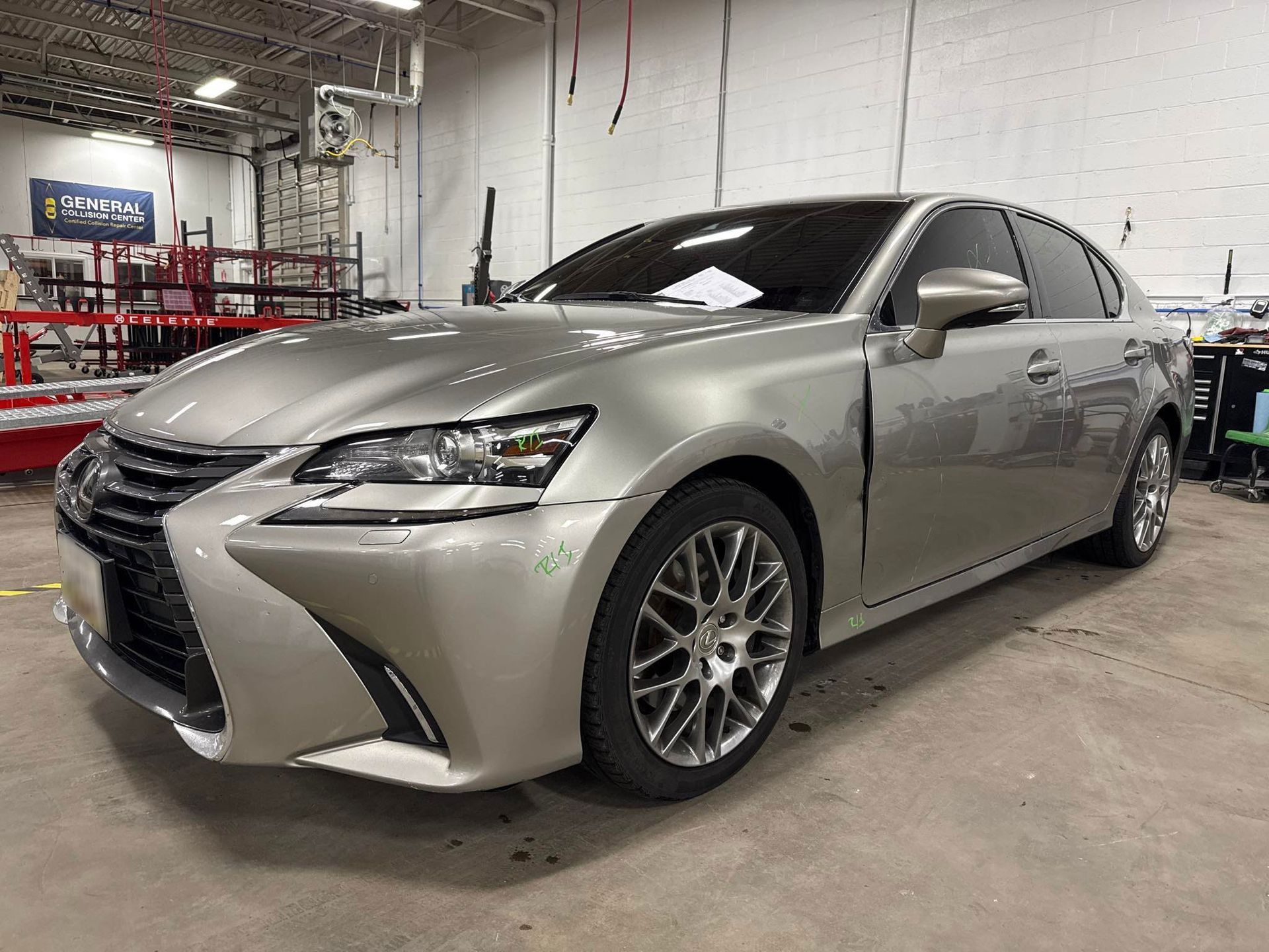 Silver Lexus GS sedan in a shop with gray walls and equipment.