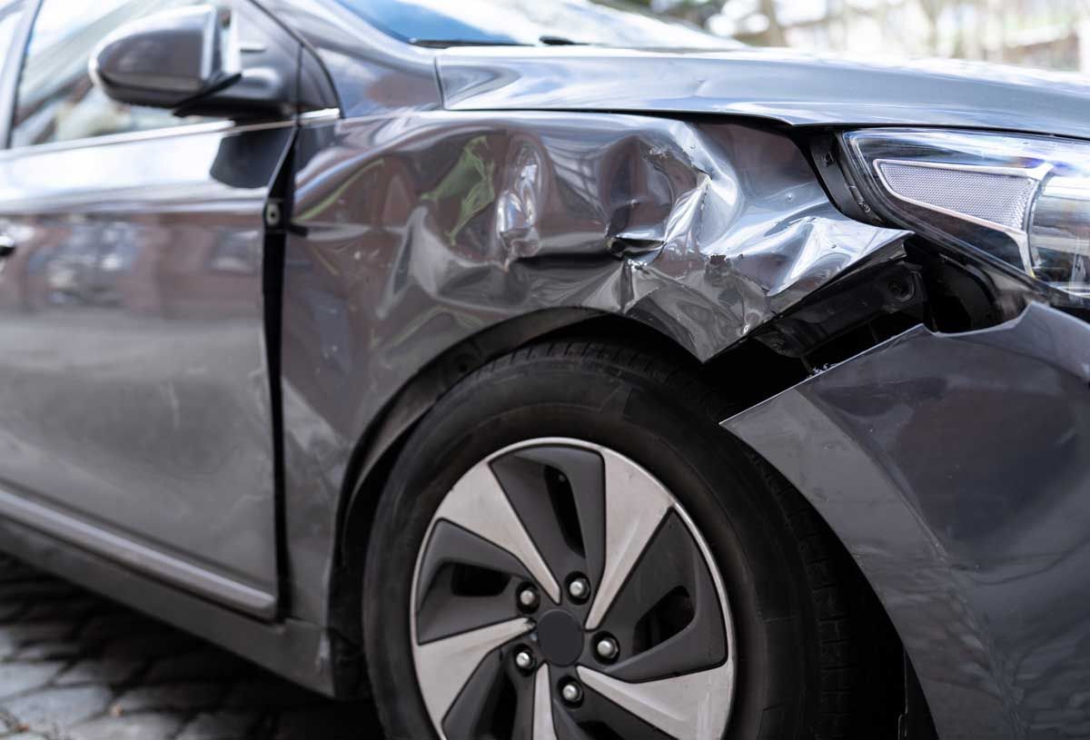 Gray car with significant damage to the front right fender, indicating a collision.