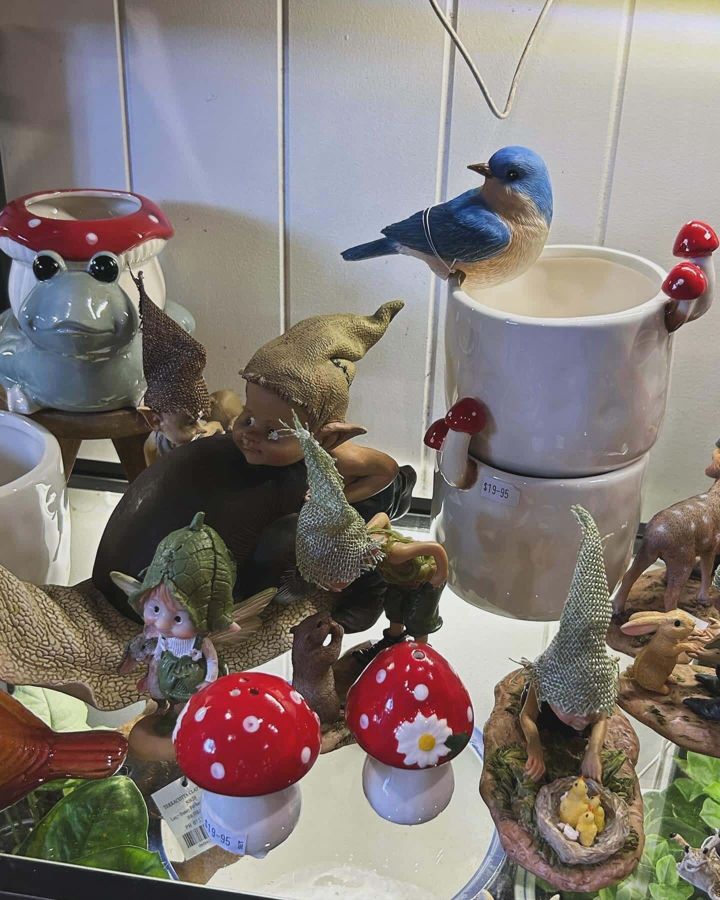 Shelf display with whimsical figurines: frog pot, bird, gnomes, mushroom decorations. — Hinterland Foliage in Maleny, QLD