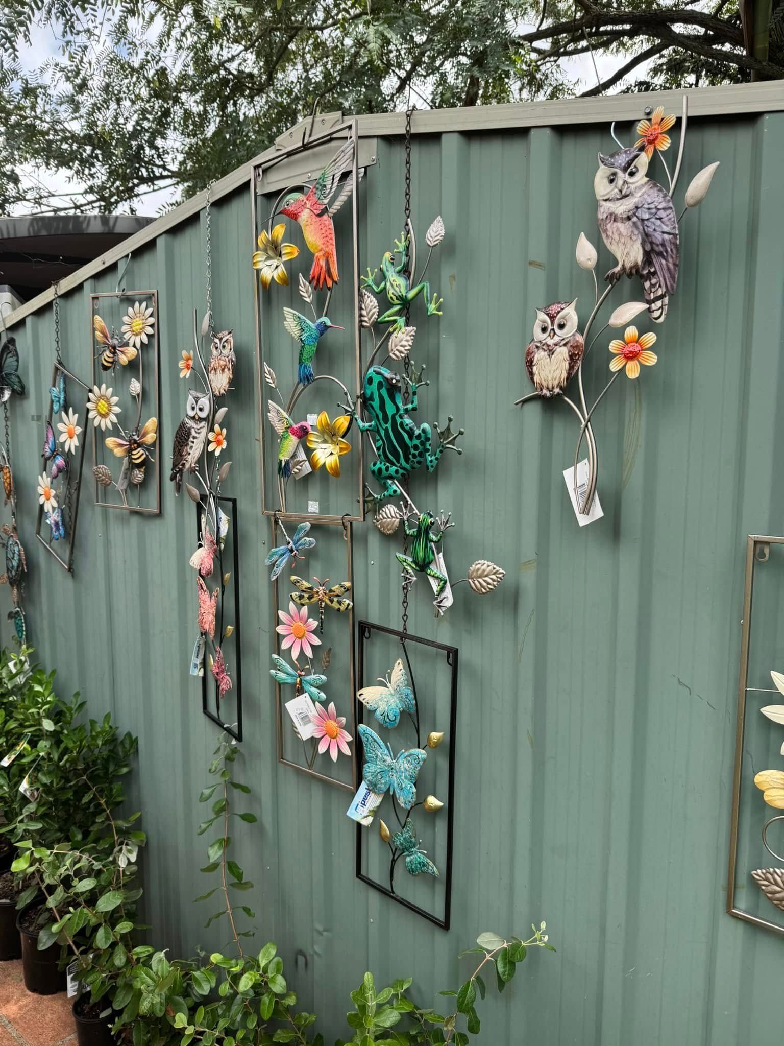 Metal Art Display of Butterflies, Flowers, and Owls on a Green Wall With Plants — Hinterland Foliage in Landsborough, QLD