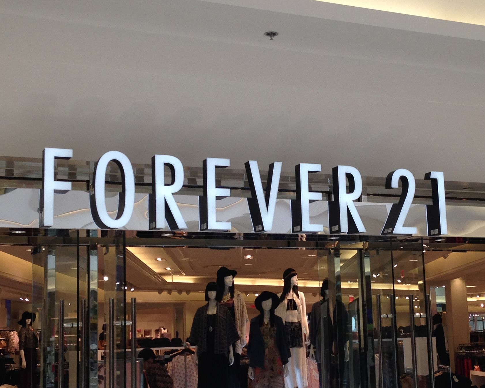 Forever 21 store entrance with mannequins in the window, under a large white and black sign.