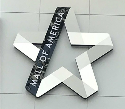 Mall of America star logo with black and white design on a light gray wall.