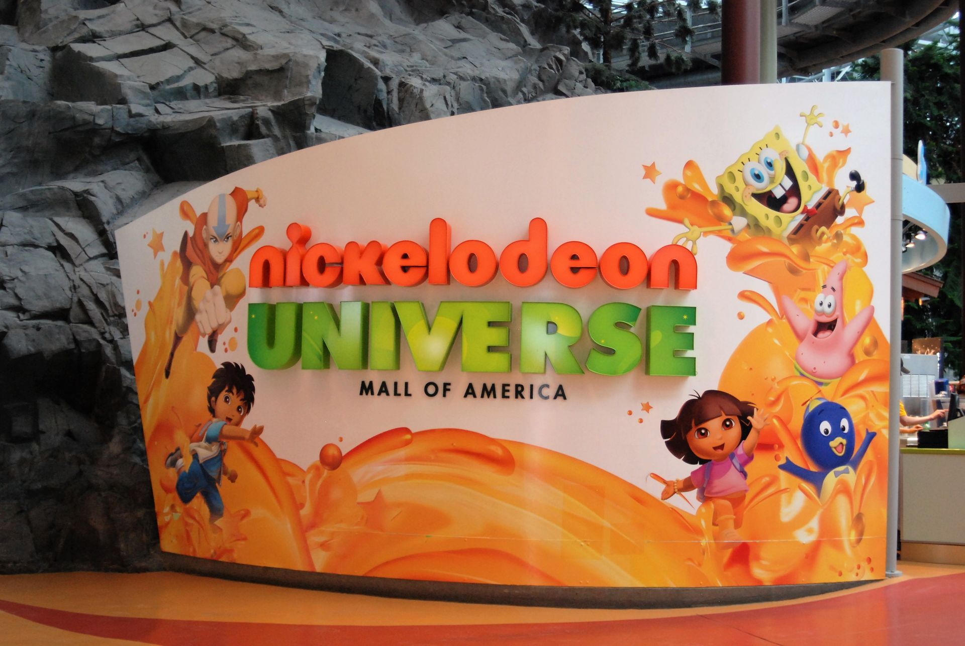 Nickelodeon Universe sign at Mall of America, with orange splash, SpongeBob, Dora, and other cartoon characters.