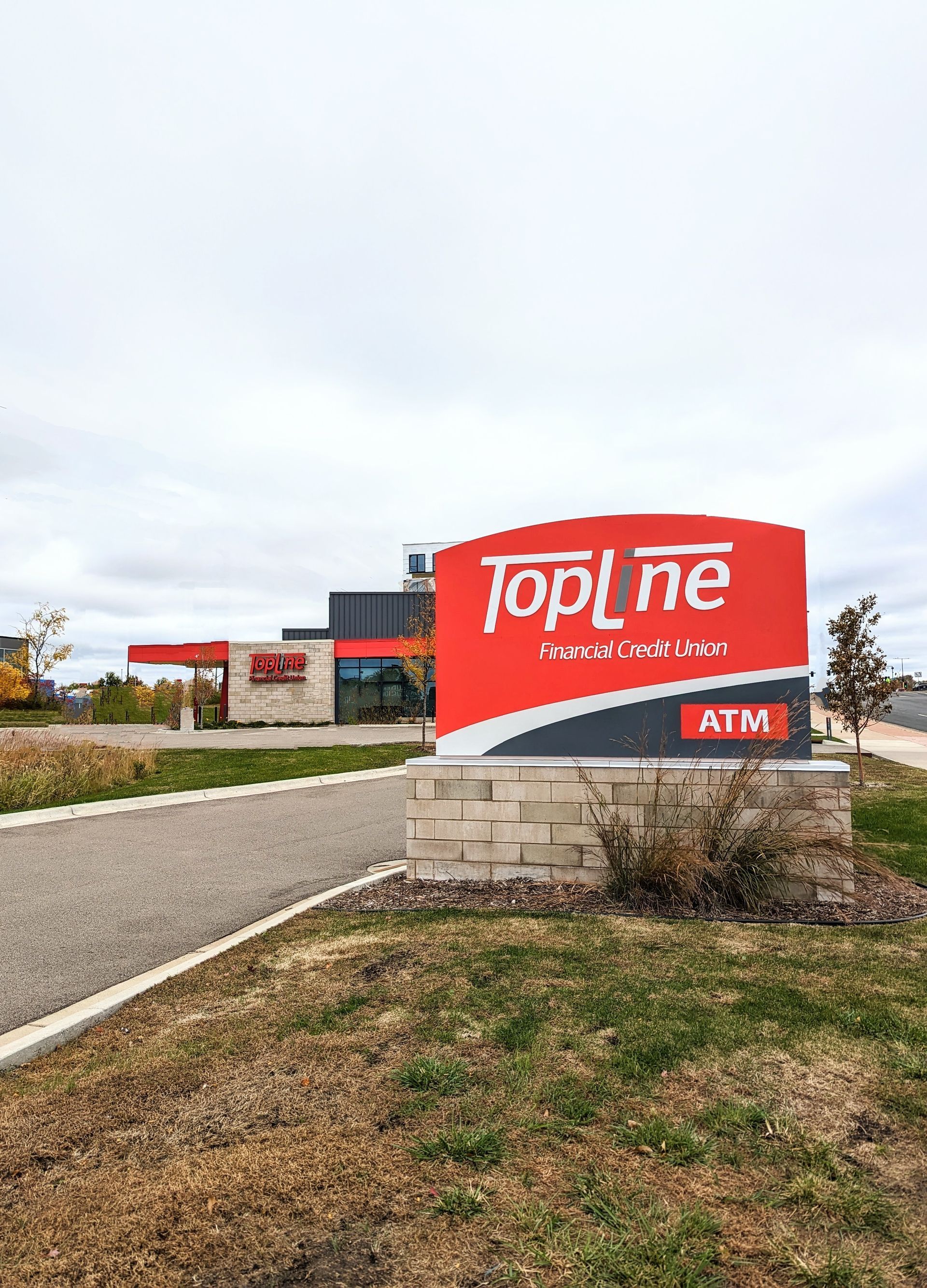 TopLine Federal Credit Union sign and building; red and white logo against a cloudy sky.