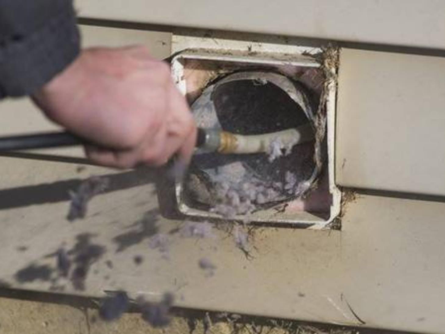 a person in a blue shirt is adjusting an air vent on the ceiling