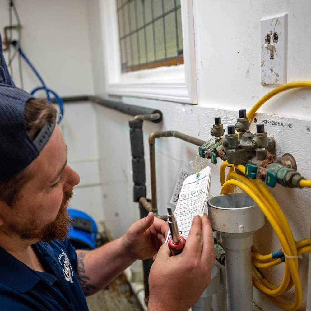 A Gary's plumber is working on a unit with a screwdriver.