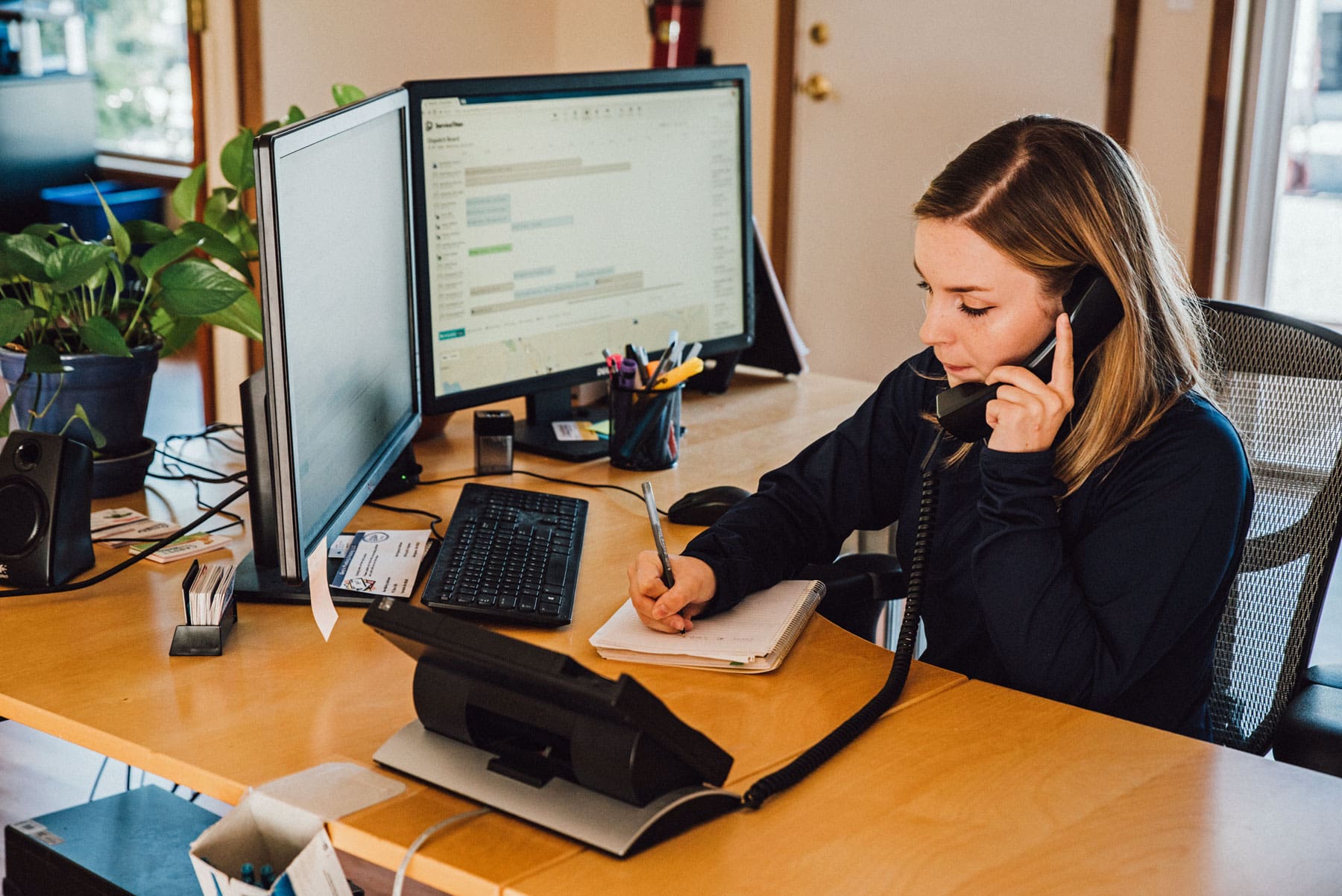 A woman is sitting at a desk talking on a phone.