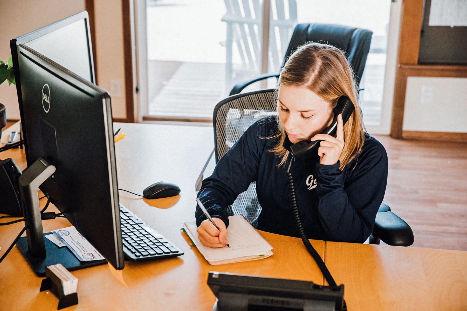 A woman is sitting at a desk talking on a phone.