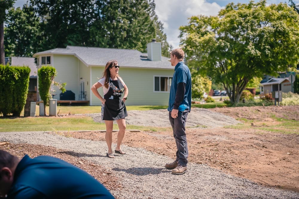 A man and a woman are standing in front of a house talking to each other.