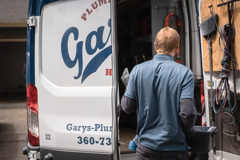 A man is standing in front of a plumbing van.