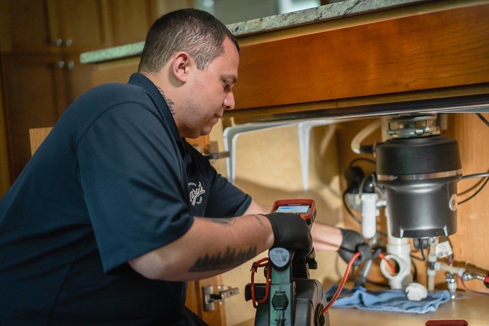A man is fixing a garbage disposal in a kitchen.