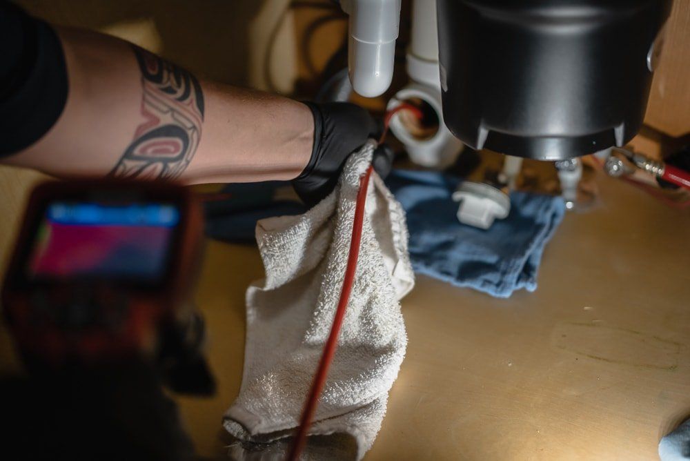 A man is cleaning a sink with a hose and a towel.