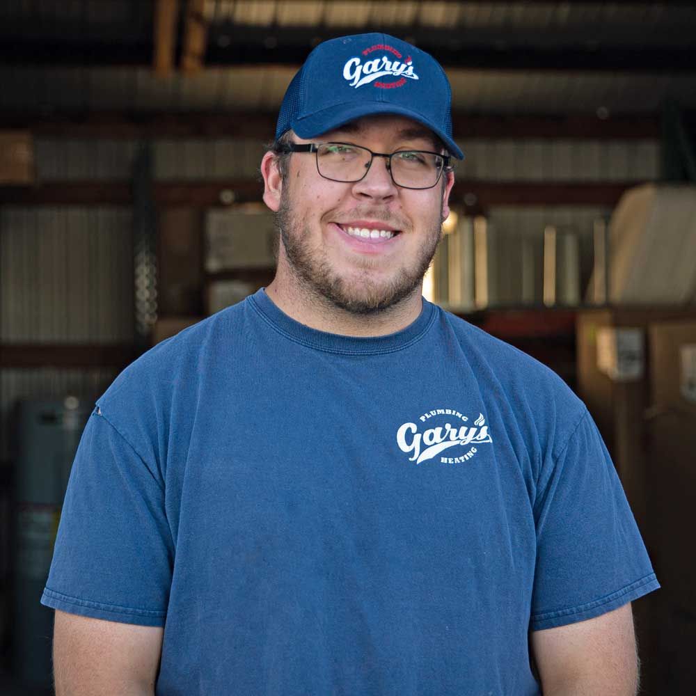A man wearing a blue shirt and a blue hat is smiling for the camera.