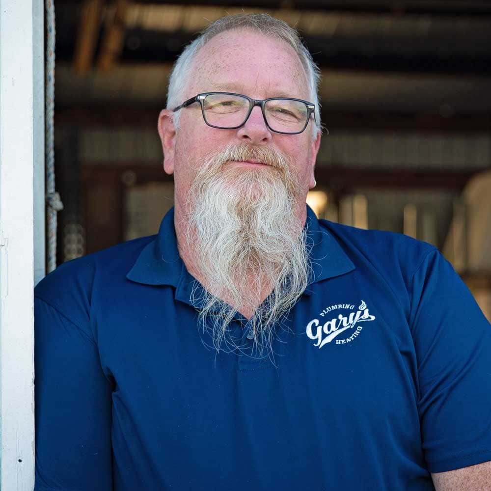 A man with a beard and glasses is wearing a blue shirt.