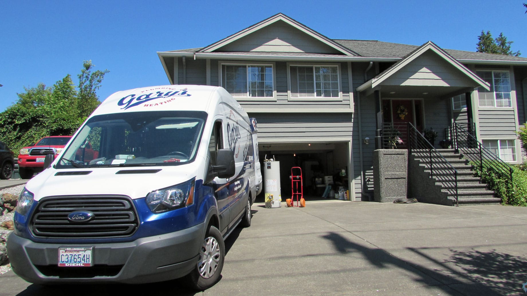 A blue and white van is parked in front of a house.