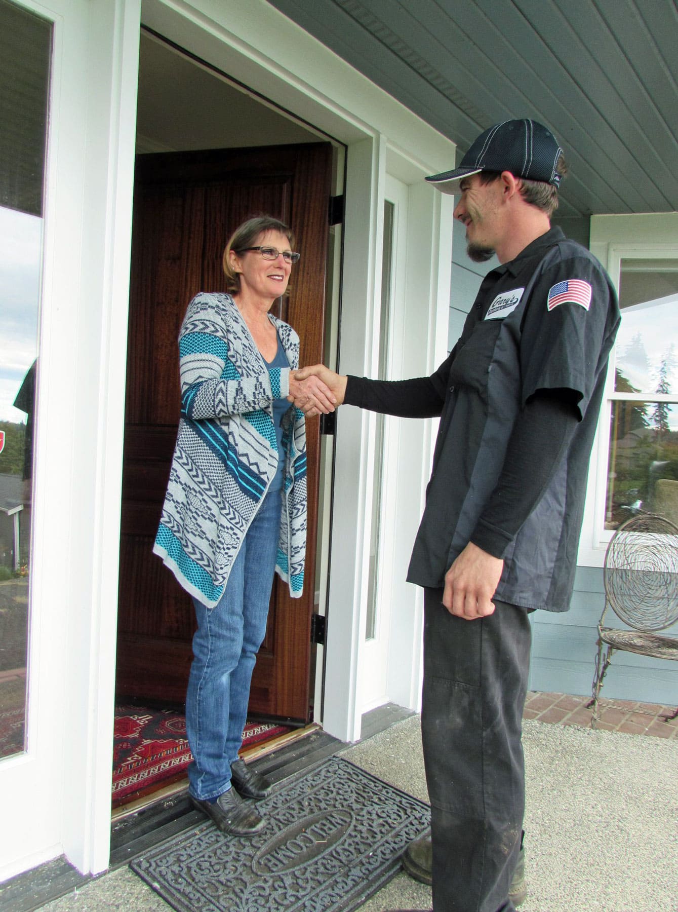 A man is shaking hands with a woman in a doorway.