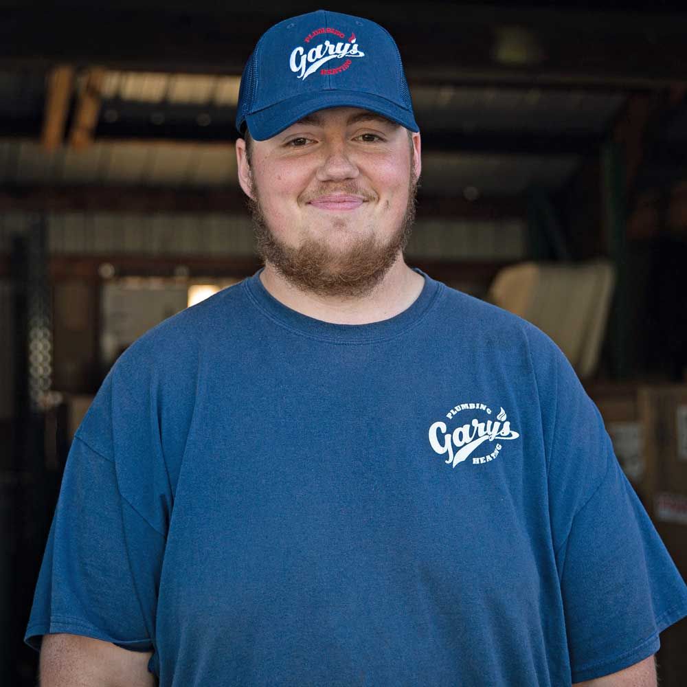 A man wearing a blue shirt and a blue hat is smiling for the camera.