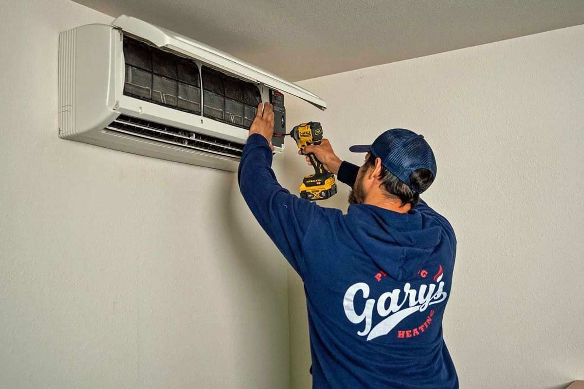 Gary's technician is installing an air conditioning unit on a white wall.