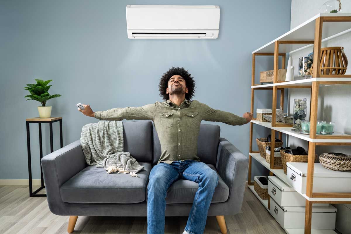 A man is sitting on a couch in a living room with his arms outstretched.