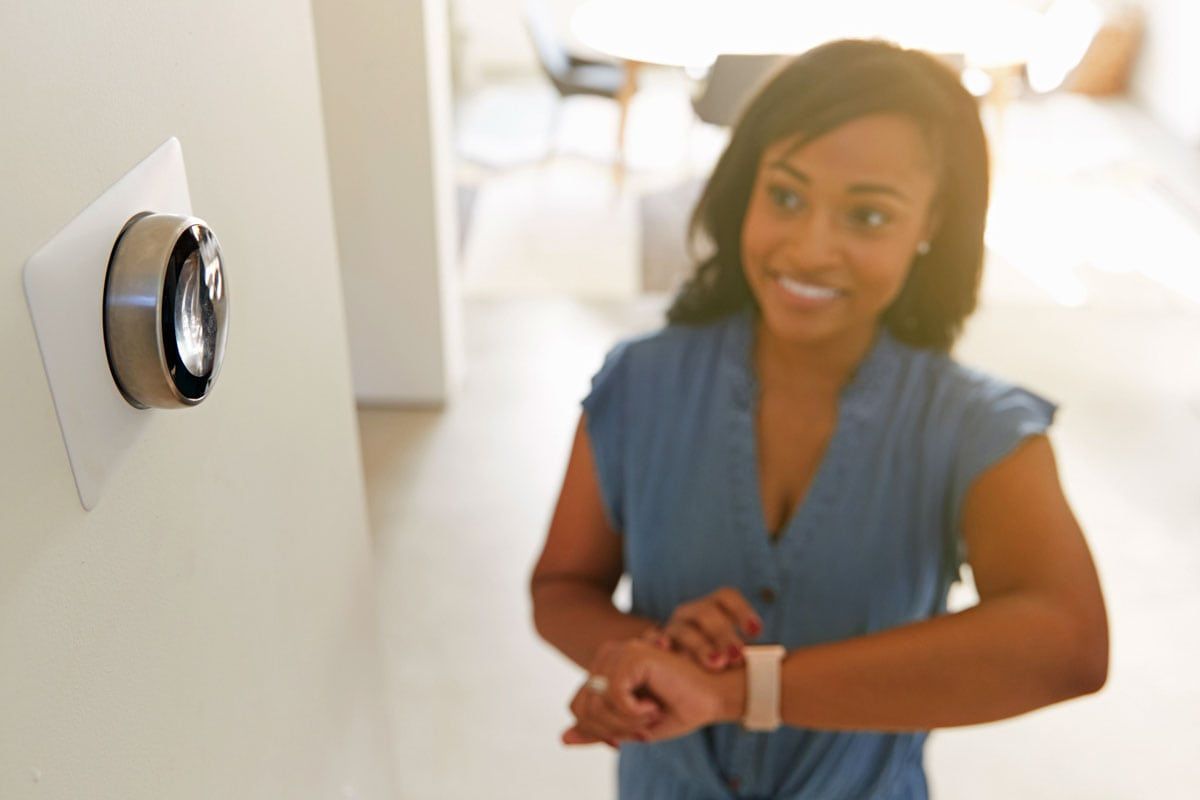 Photo of a woman using a smart thermostat