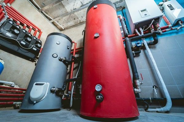 Two water heaters are sitting next to each other in a room.