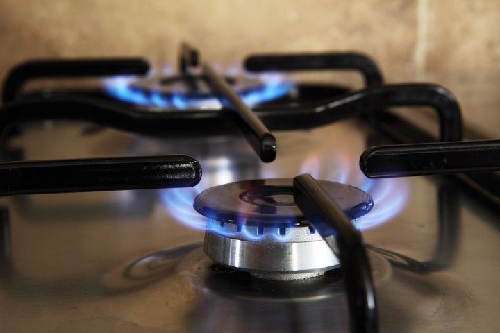 A close up of a gas stove with a blue flame coming out of it.
