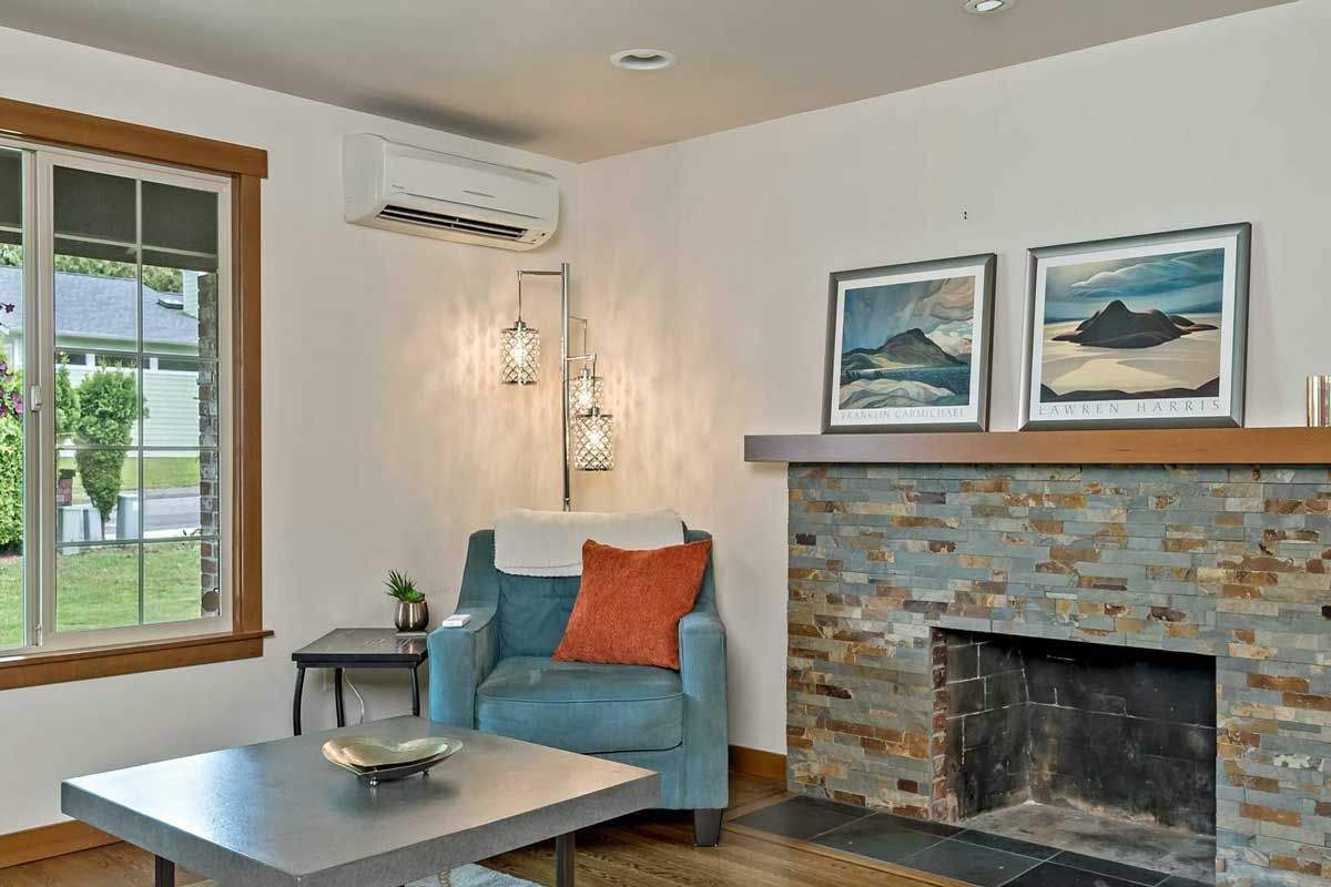 A living room with a fireplace , chair , table and window.