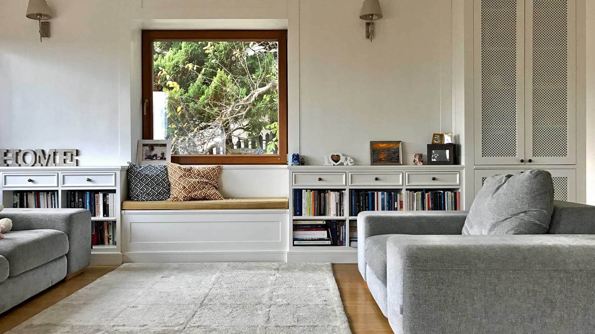 A living room with a couch , chair , bookshelf and a window.