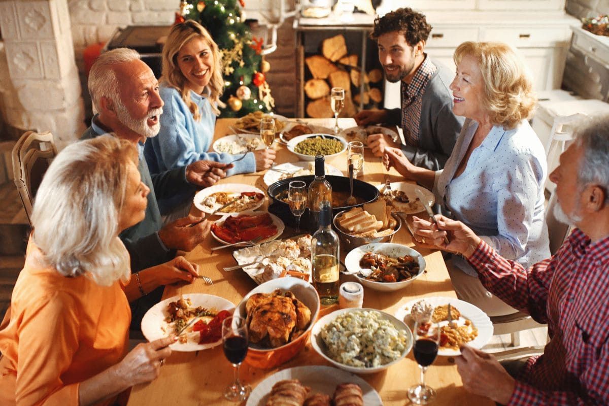 A large family is sitting around a table eating christmas dinner.