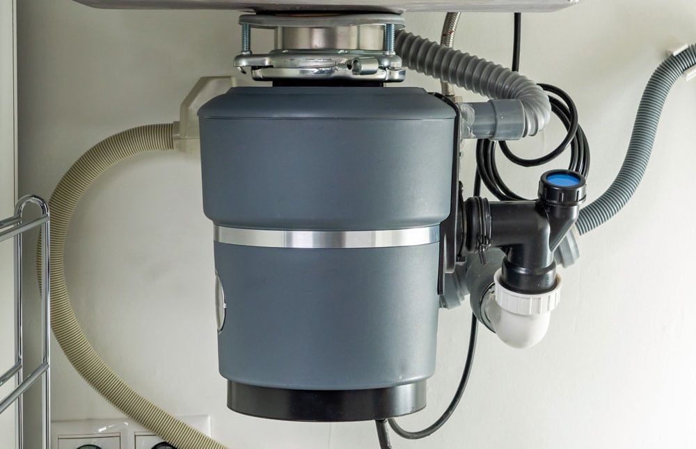 A garbage disposal is under a sink in a kitchen.