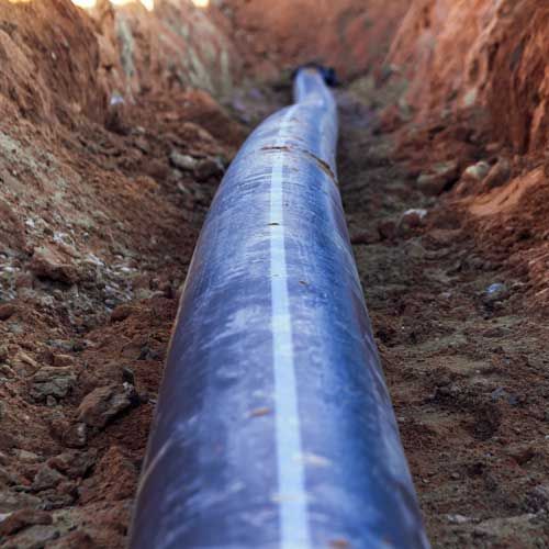 Black pipe with white stripe in a brown trench.