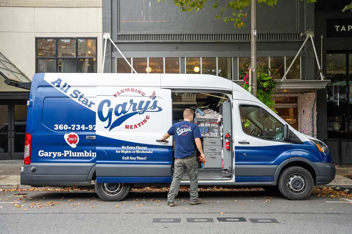 A technician is standing next to a blue and white van that says gary 's plumbing