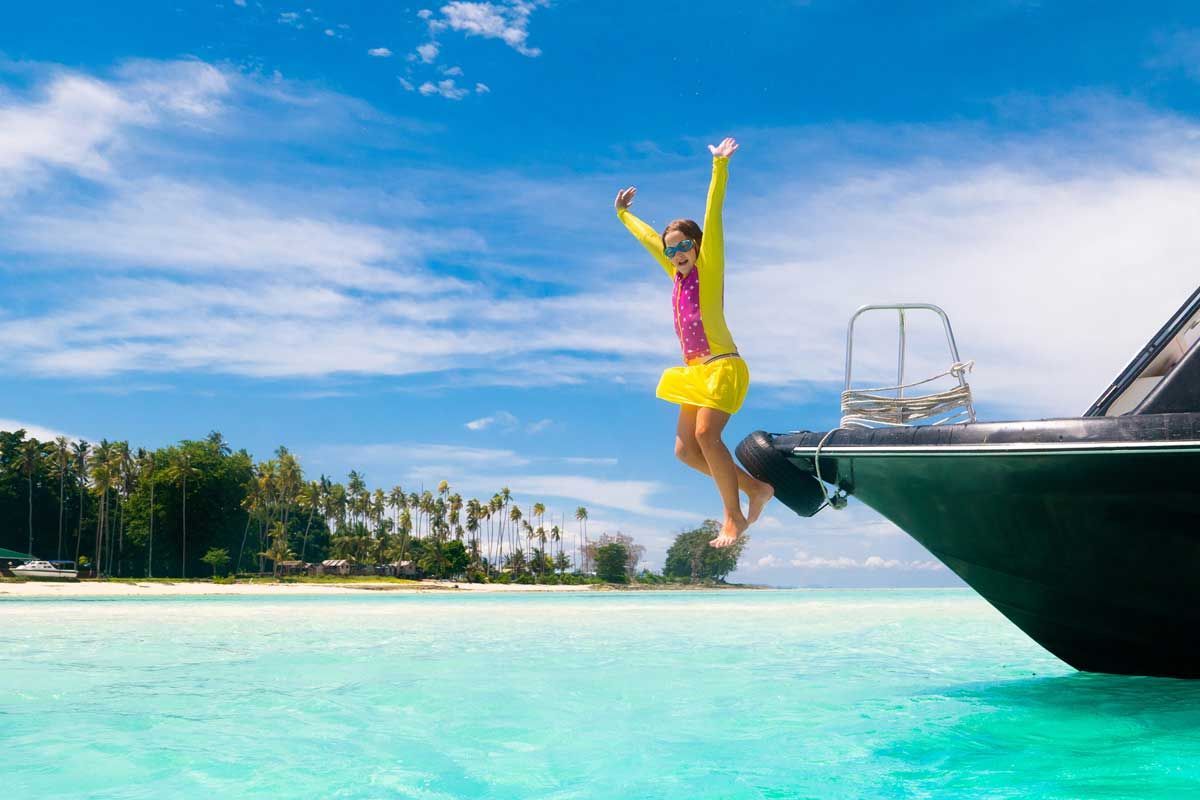 A person is jumping off the side of a boat into the ocean.