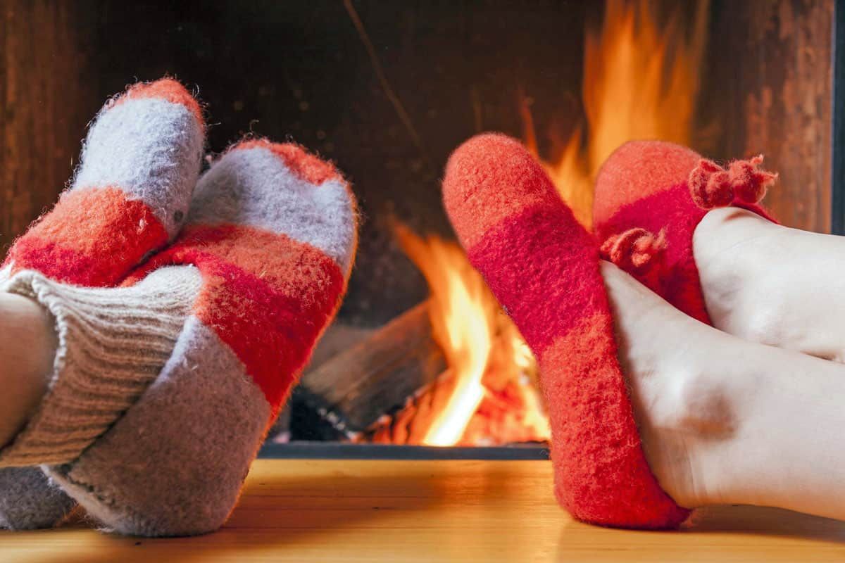 Photo of two people in front of a fireplace enjoying a cozy warm home