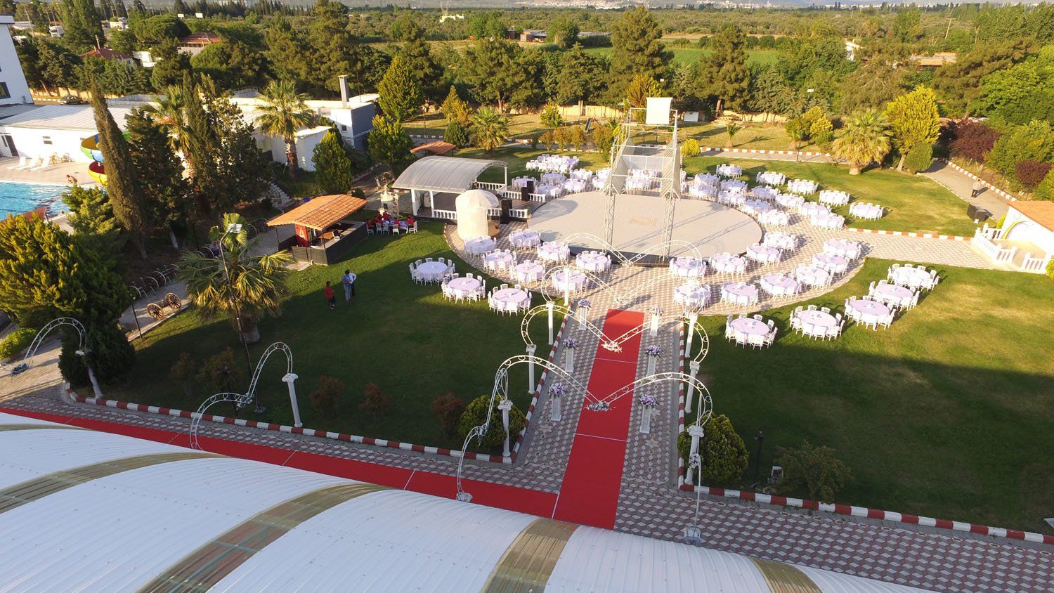 An aerial view of a wedding venue with tables set up and a red carpet.