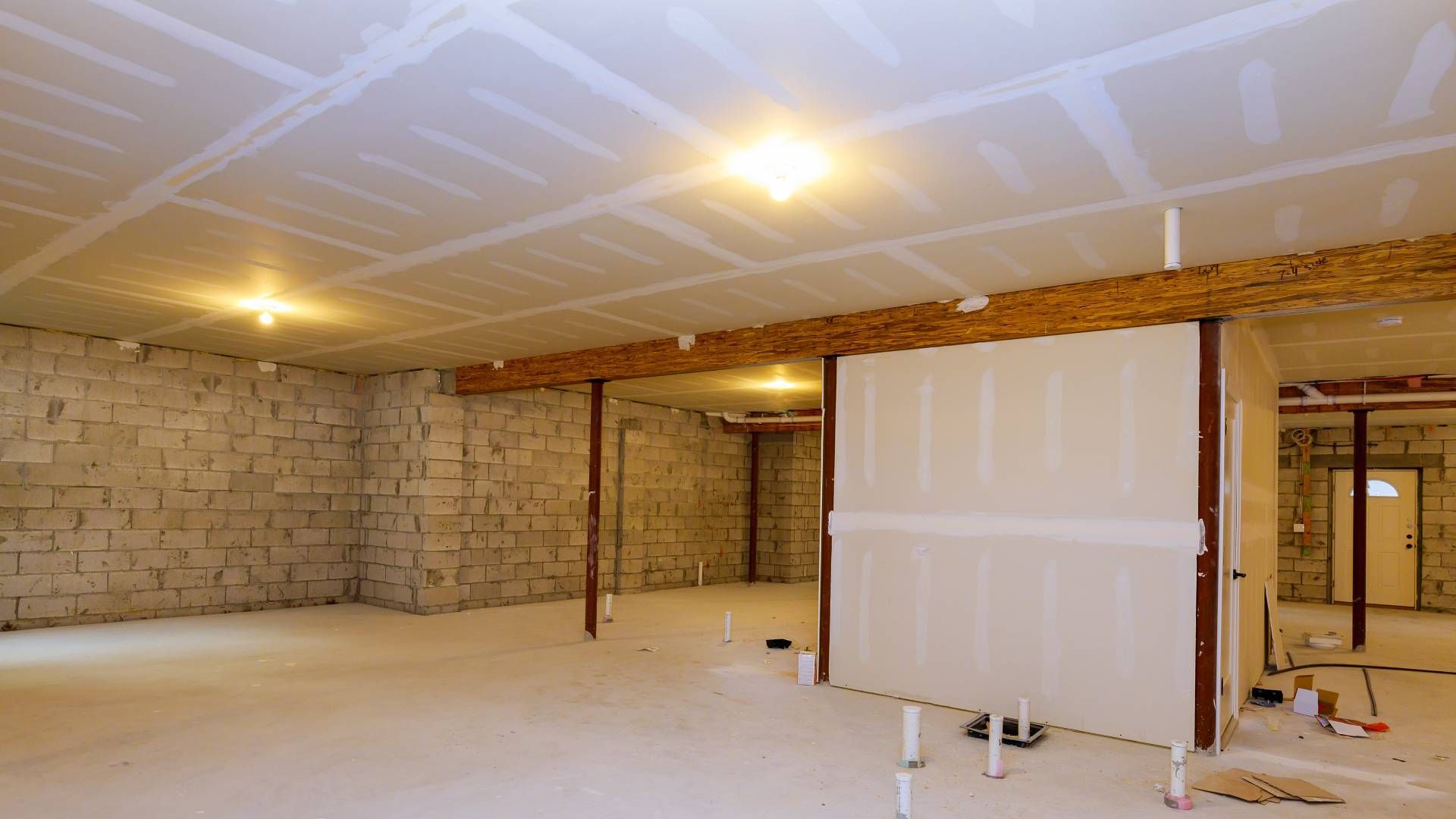 Basement renovation in progress. Drywall, beams, concrete block walls.