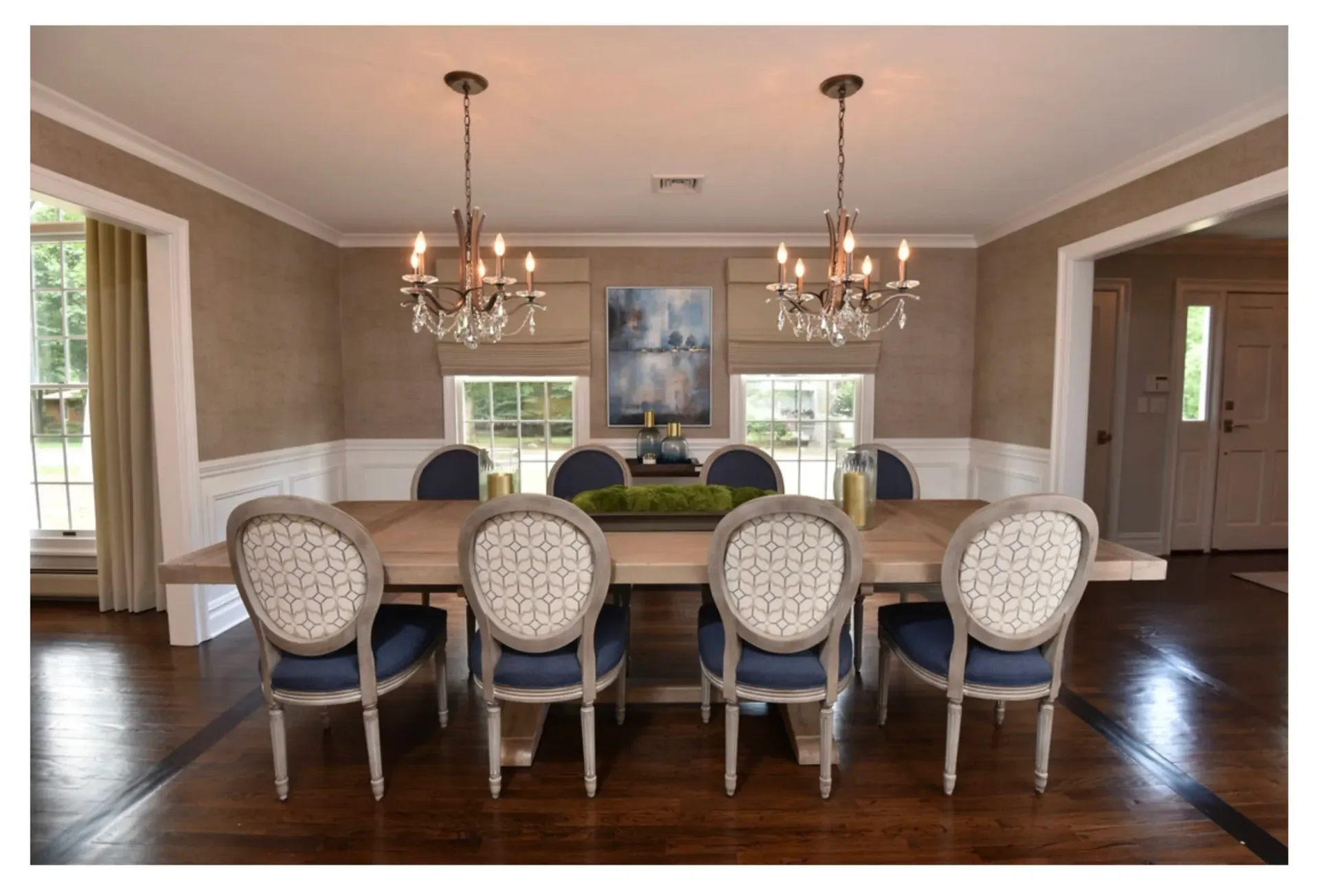 Elegant dining room with a long table, blue chairs, and crystal chandeliers.
