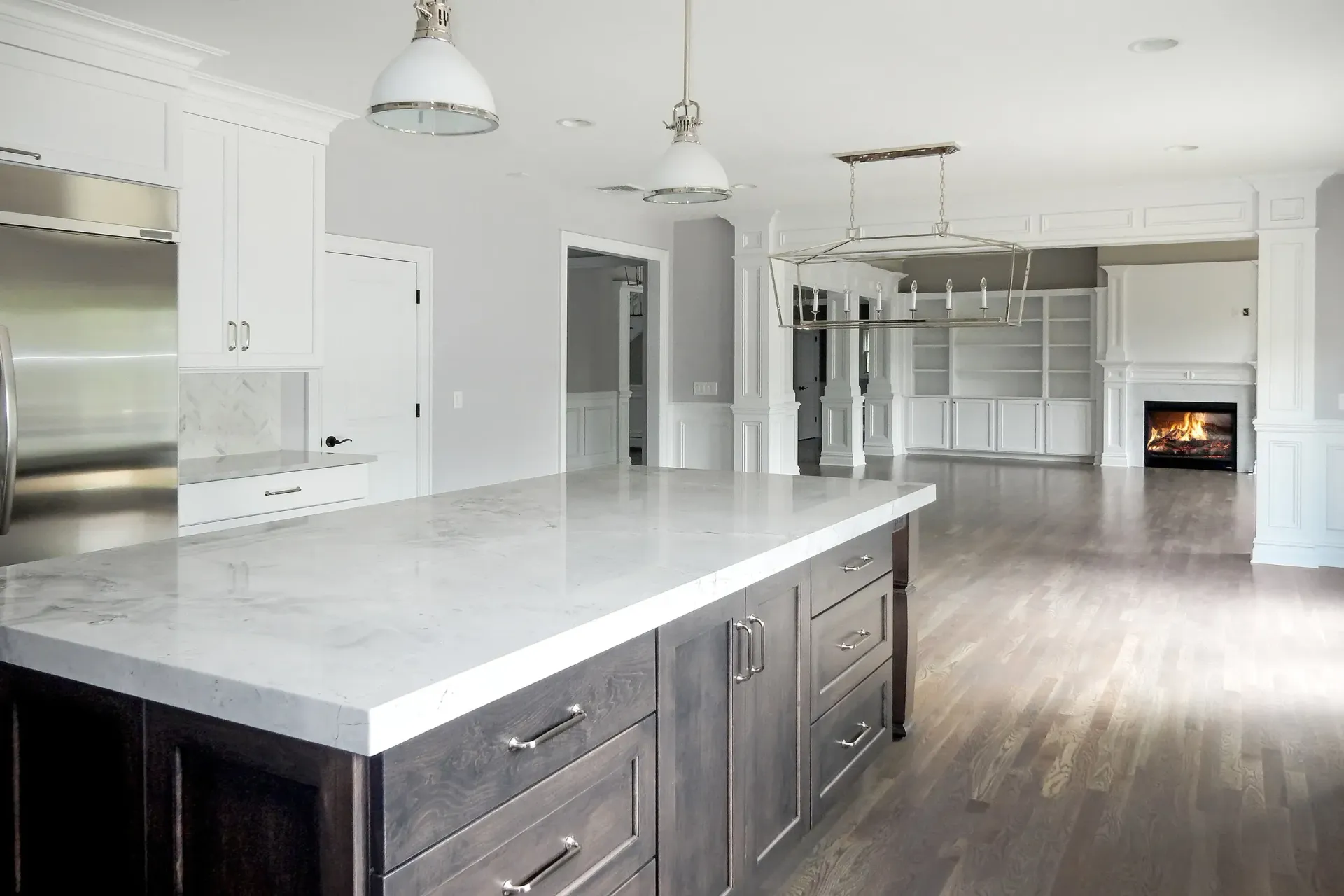 Spacious, modern kitchen with large island, stainless steel appliances, and view of living area with fireplace.