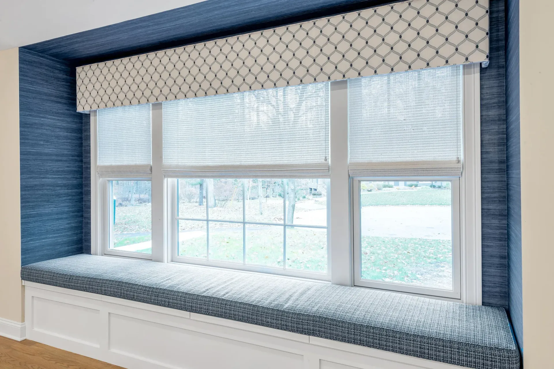 Window seat with blue textured walls, patterned valance and cushion.