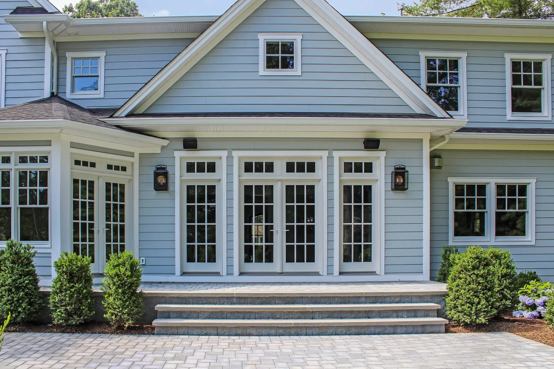 Light blue house with white trim, French doors, and stone steps.