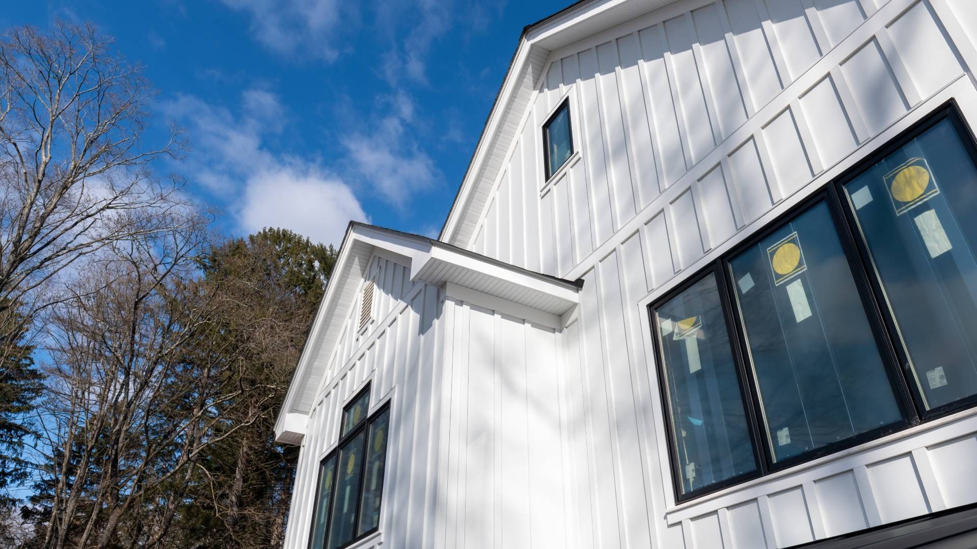 White farmhouse exterior with black-framed windows against a blue sky.