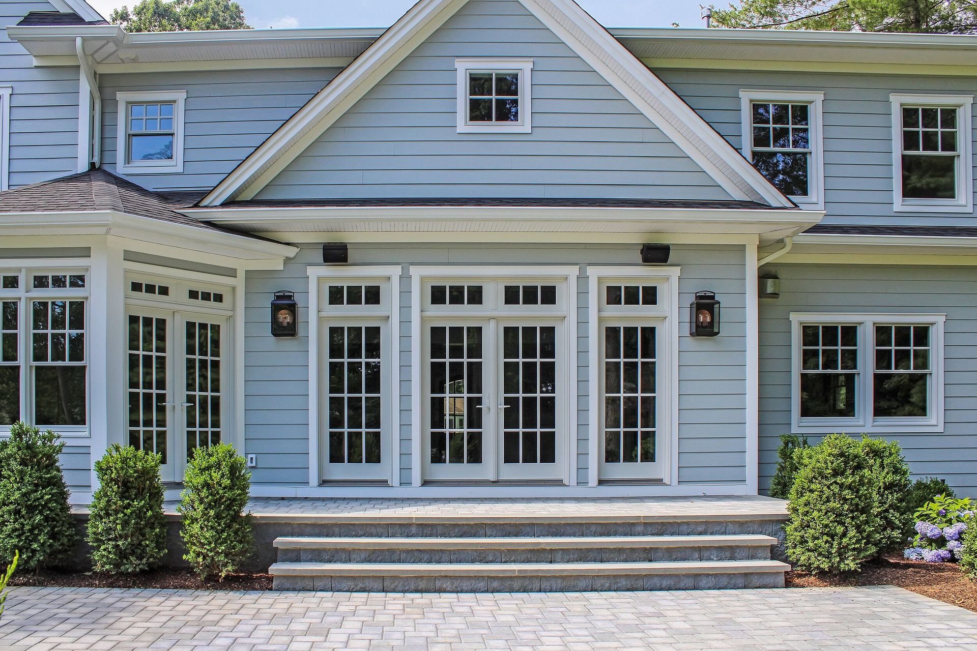 Blue house with white trim, french doors, and steps leading to the entrance.