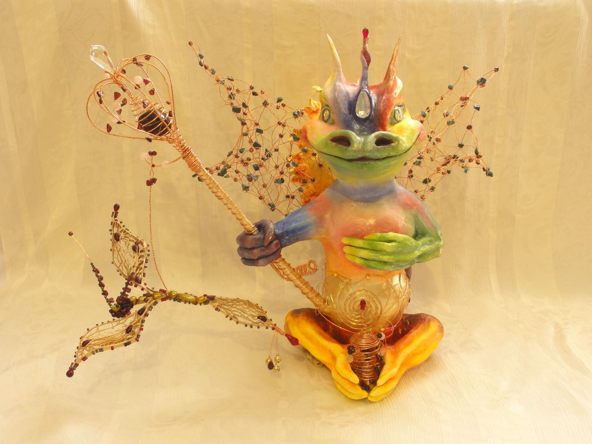 Eine bunte Figur eines Regenbogen-Drachen der einen Zauberstab hält