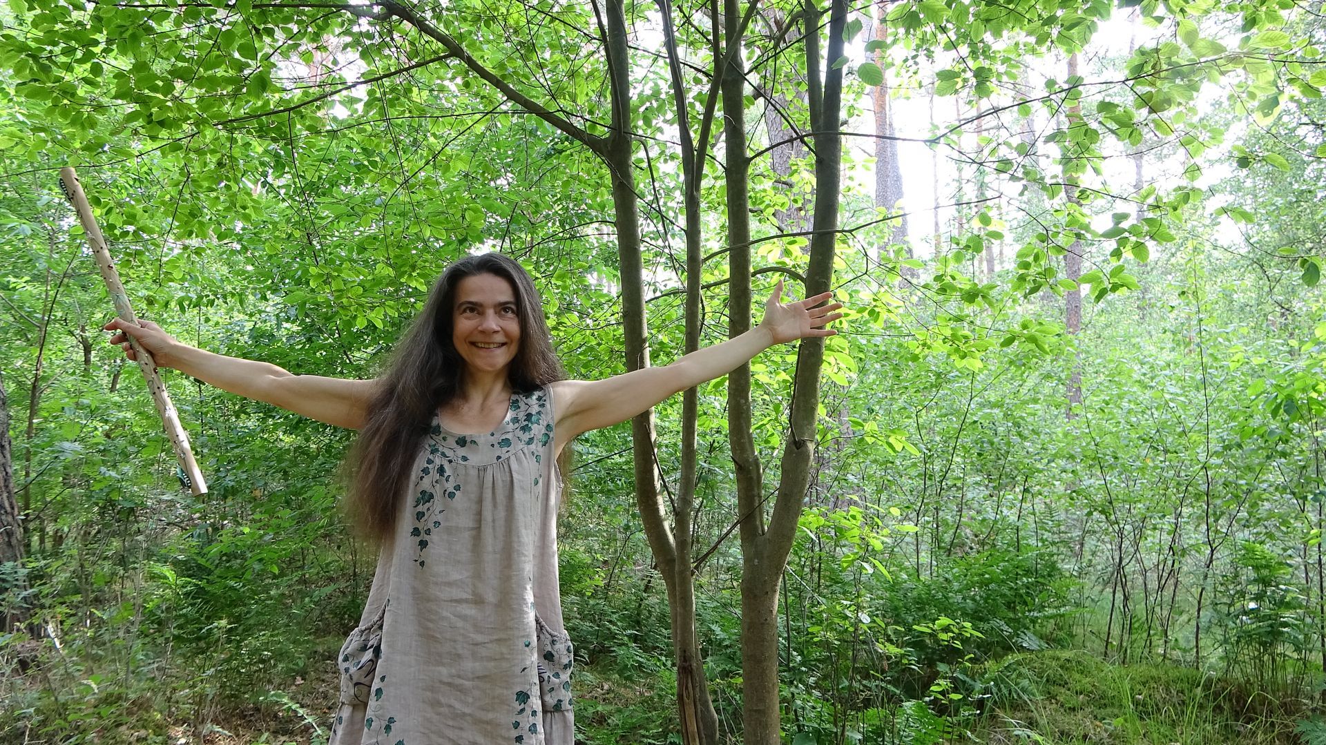 Eine Frau steht im Wals im Kleid und hat die Arme ausgestreckt