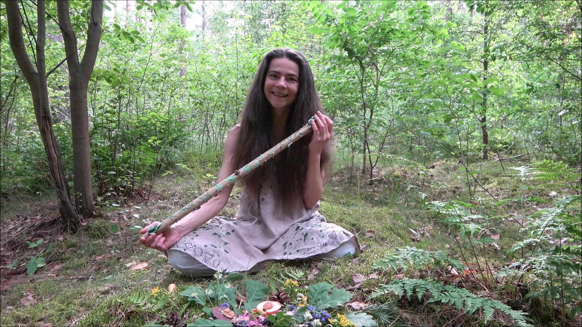 Eine Frau sitzt im Wald mit einer Bambusflöte