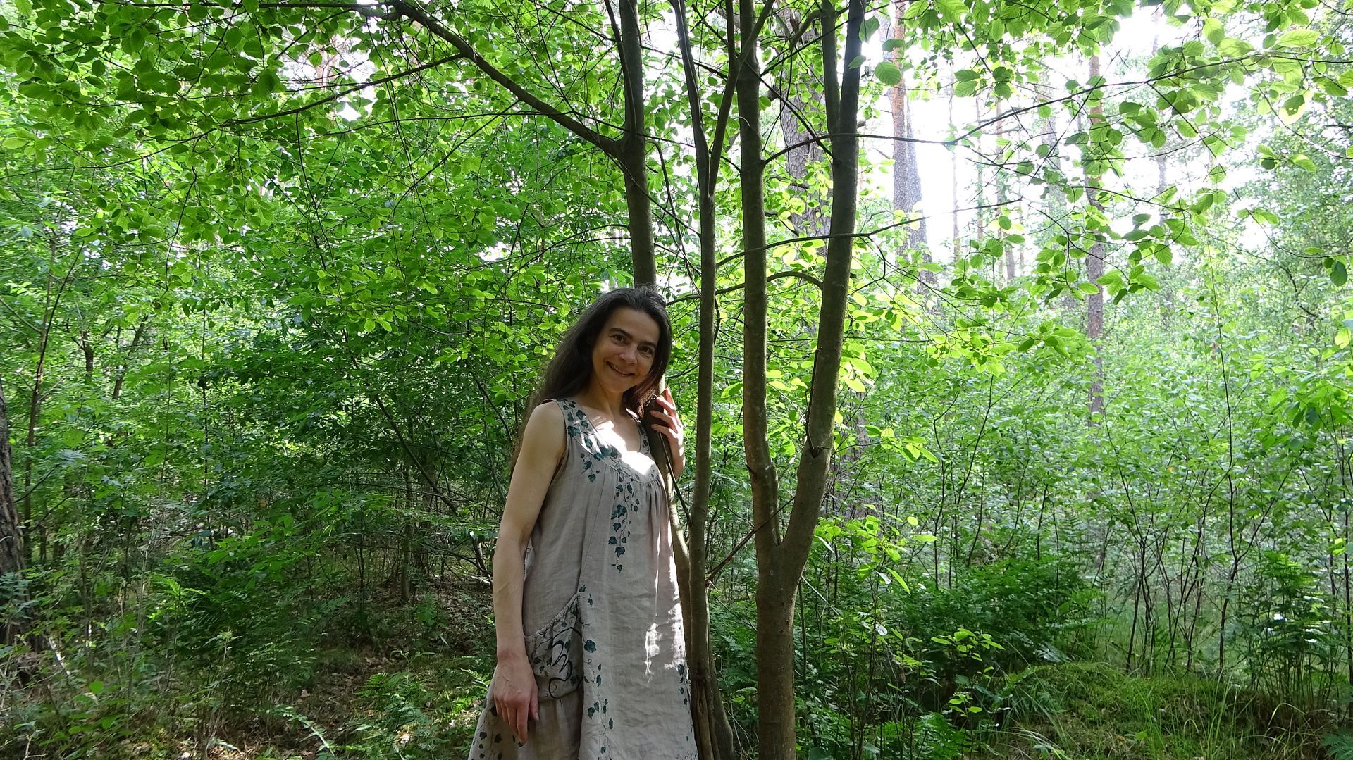 Eine Frau im Kleid umarmt einen Baum