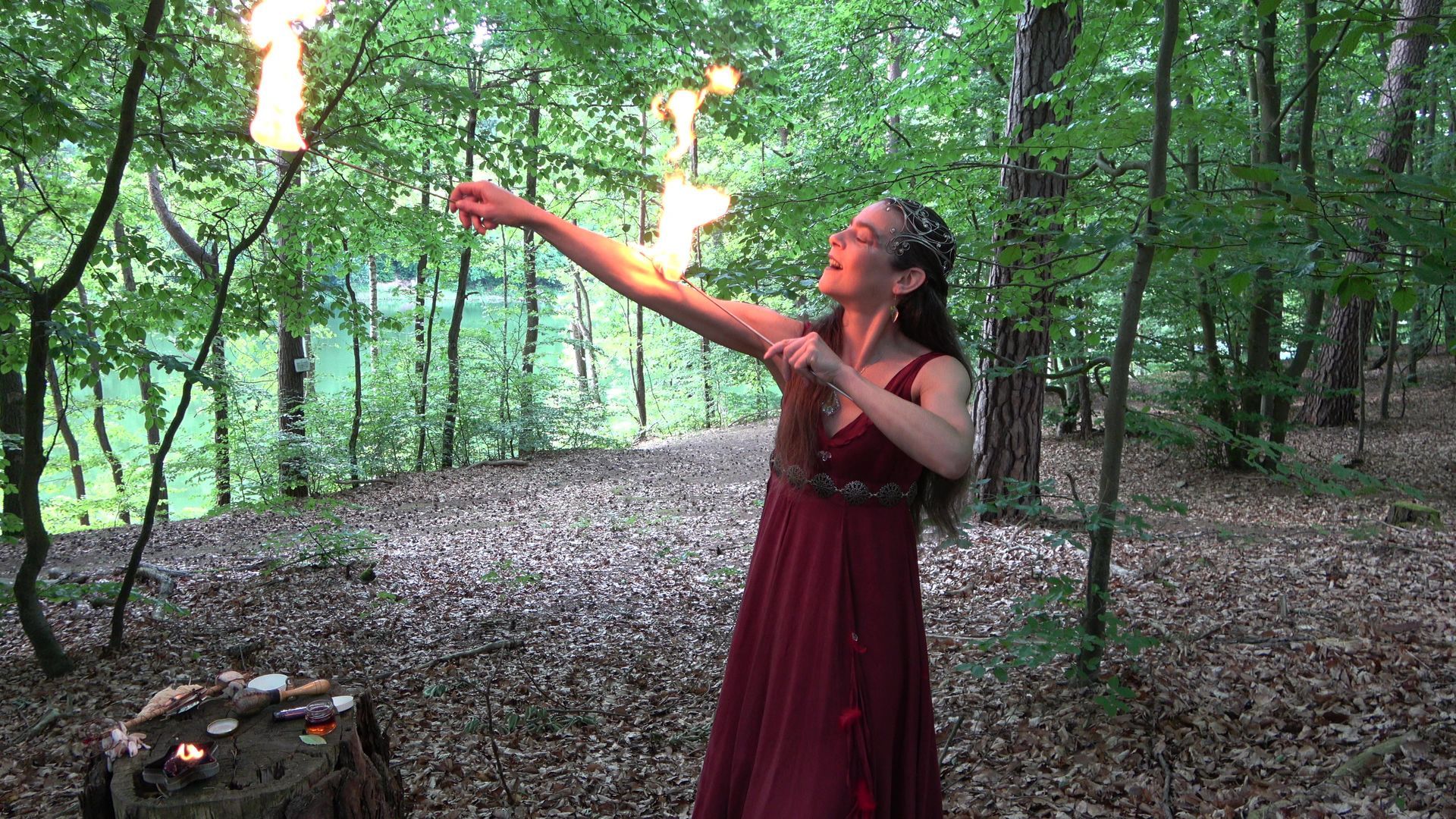 Eine Frau im Feenkleid berührt ihren Arm mit Feuer