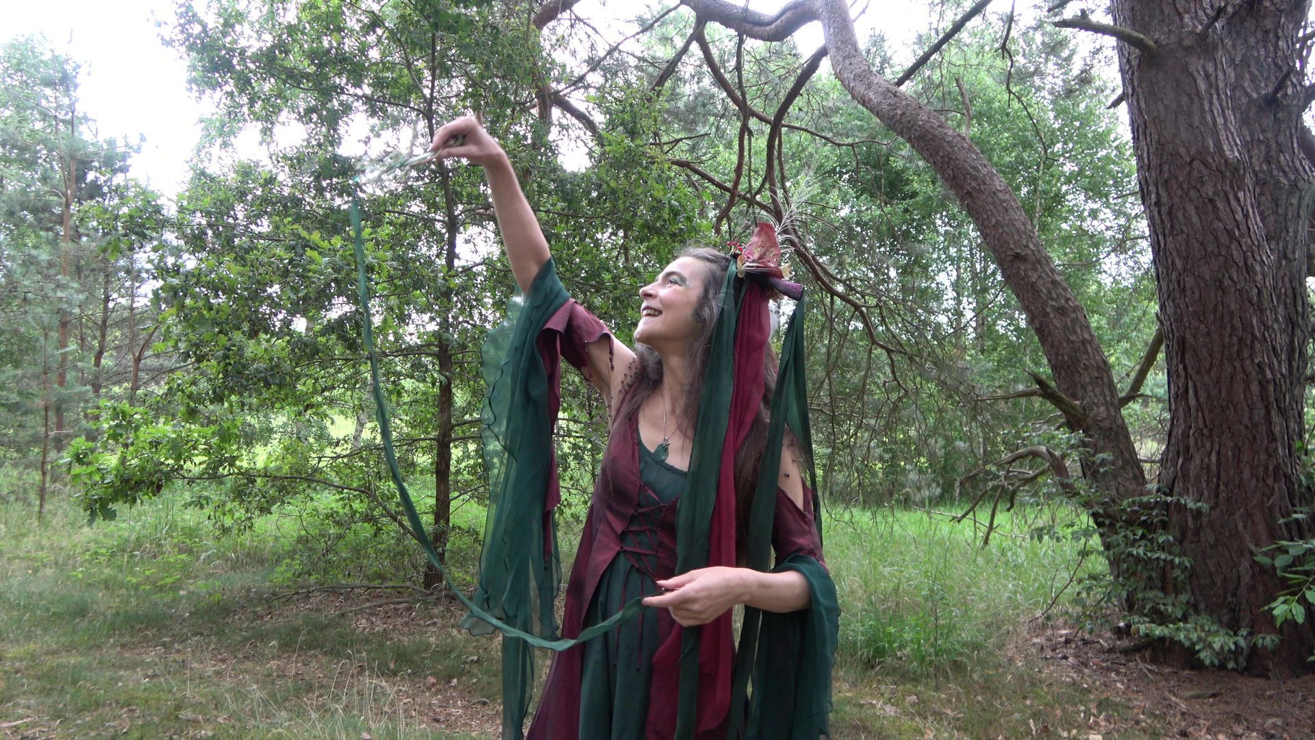 Eine Frau im grünen Feenkleid steht im Wald