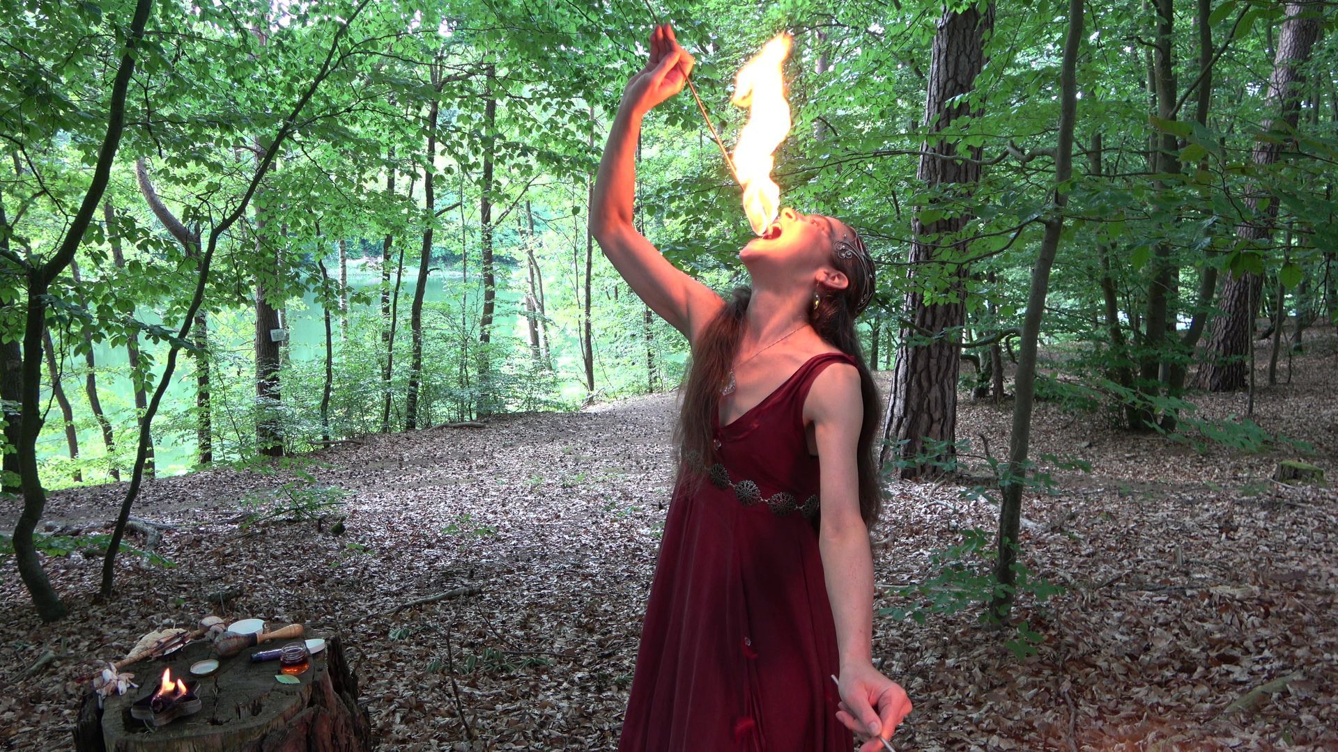 Eine Frau im roten Kleid schluckt im Wald Feuer